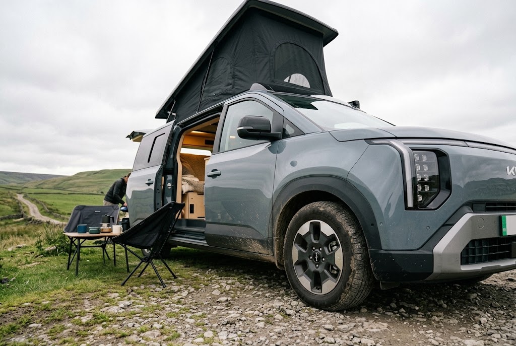 Kia PV5 pop top camper parked up with the roof raised and side door open
