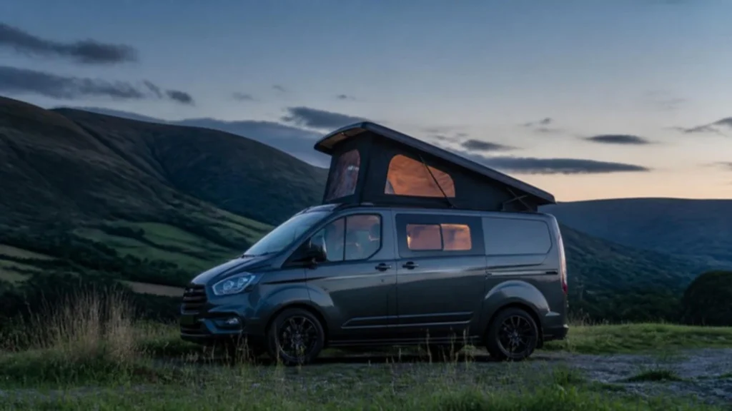 Pop top campervan with scenic canvas raised at dusk in the hills